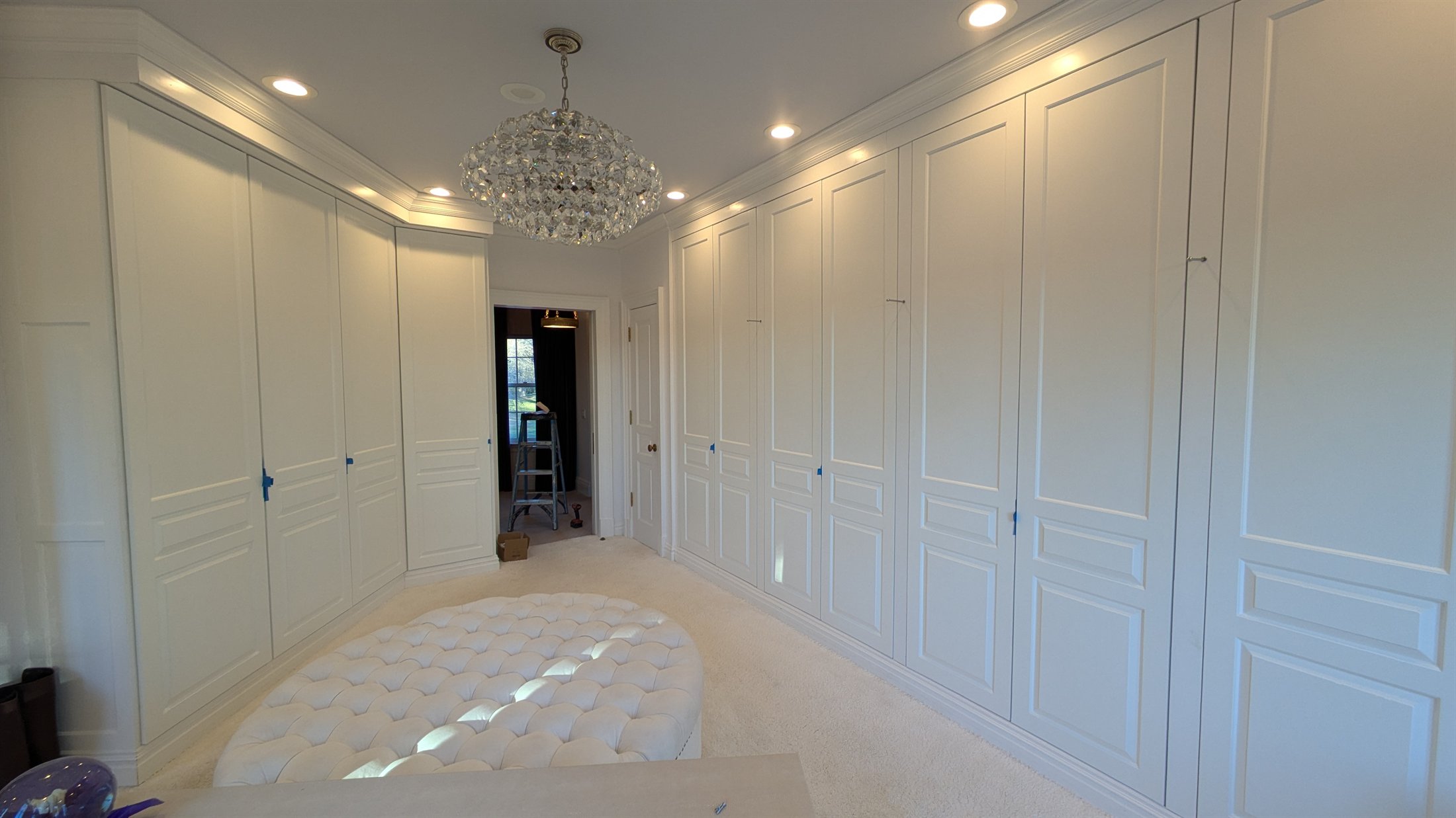 Floor-to-ceiling white built-in storage wrapping a walk-in closet